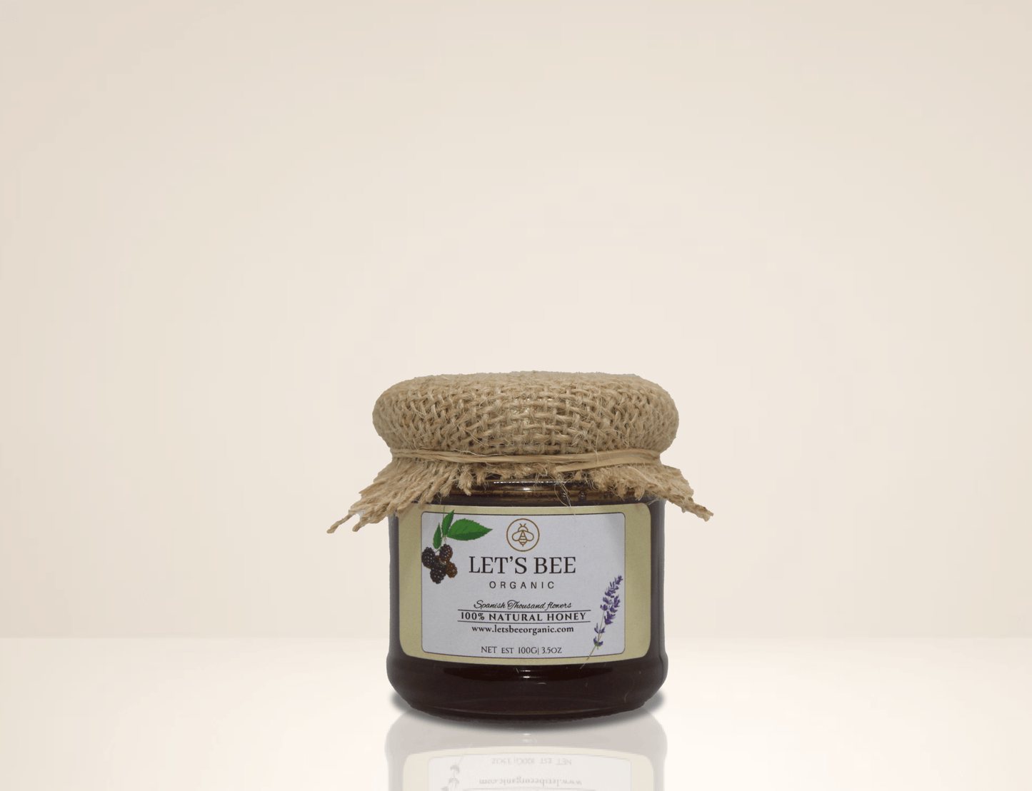 100G jar of Organic thousand flowers honey, jar decorated with a beautiful sticker and a piece of textil on top.