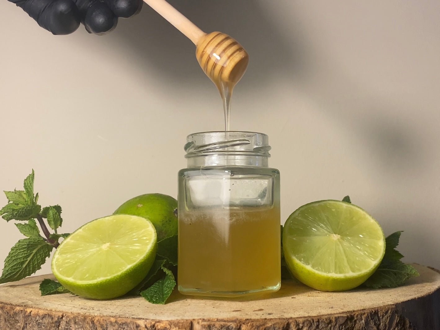 Organic lime honey for sale on top of a log with 2 slices of lime next to it and mint, direct flavour to your mouth with a unique flavor